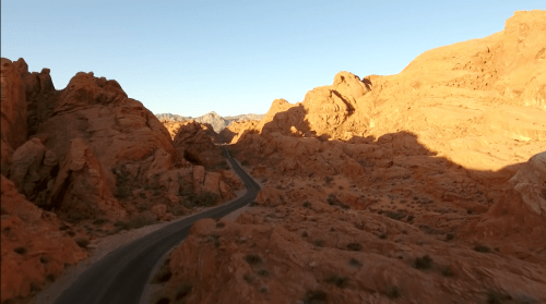 A winding road through vibrant red rock formations under a clear blue sky.