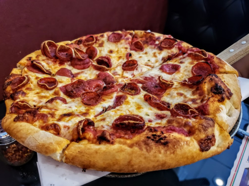 A large pepperoni pizza with a golden crust, topped generously with slices of pepperoni and melted cheese.