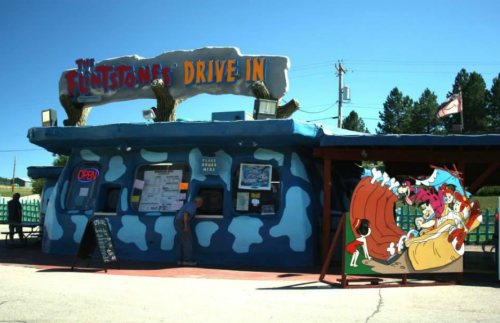A colorful drive-in restaurant themed after The Flintstones, featuring cartoon characters and a bright blue exterior.