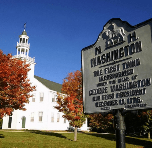 Historic sign for Washington, NH, with a white church and vibrant autumn foliage in the background.