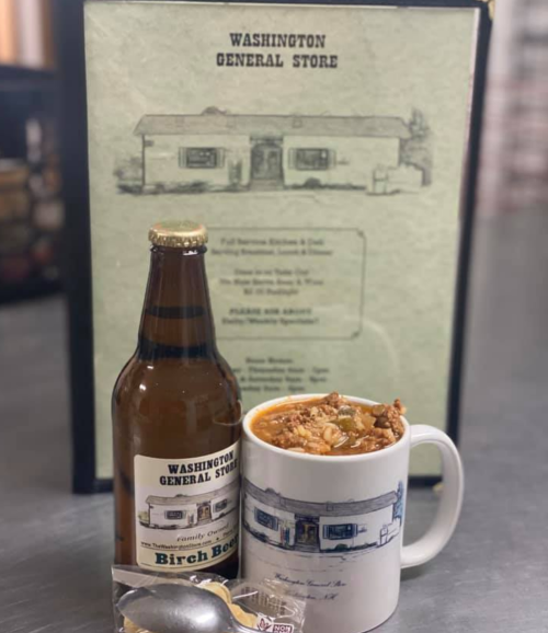 A bottle of Birch Beer and a mug of soup sit on a table next to a menu for Washington General Store.