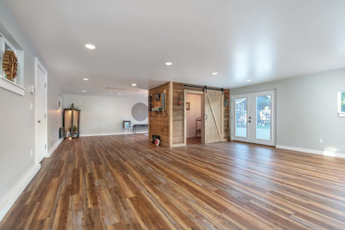 Spacious, modern interior with wooden floors, sliding barn door, and large windows letting in natural light.