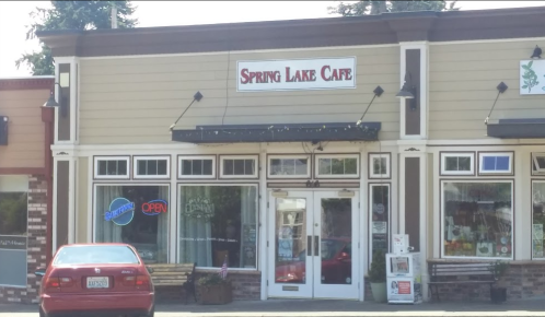 Front view of Spring Lake Cafe, featuring a sign, large windows, and an "Open" neon sign. A red car is parked outside.