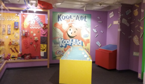 Colorful exhibit featuring Kool-Aid memorabilia, with a large Kool-Aid mascot mural and interactive display.