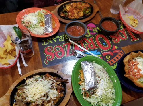A vibrant table spread with various Mexican dishes, including sizzling fajitas, tacos, salsa, and tortilla chips.