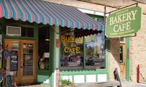 A charming bakery and café with a colorful awning, open sign, and inviting entrance.