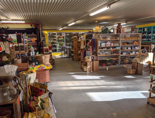 A cozy shop interior filled with shelves of various goods, crafts, and decorations, illuminated by overhead lights.