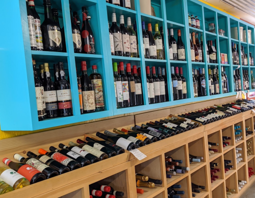 A colorful display of wine bottles on shelves, with various labels and types arranged neatly.