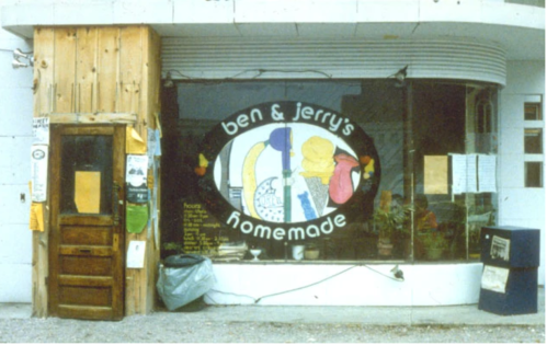 A vintage Ben & Jerry's storefront with a colorful sign and wooden door, featuring a menu displayed in the window.