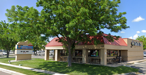 A restaurant with a red roof and outdoor seating, surrounded by trees and a sign for "Soda Crazy."