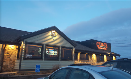 Exterior of a restaurant named "Chili's," featuring a stone facade and illuminated signage at dusk.