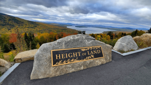 A scenic view from Height of Land, featuring colorful autumn foliage and a lake under a cloudy sky.