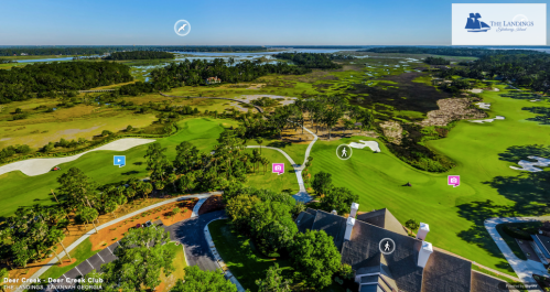 Aerial view of a golf course with lush greens, water features, and a clubhouse in the foreground.
