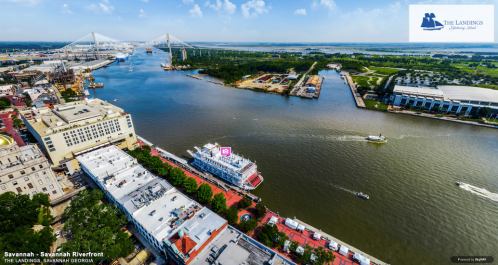 Aerial view of the Savannah Riverfront, featuring boats, buildings, and the Talmadge Memorial Bridge in the background.