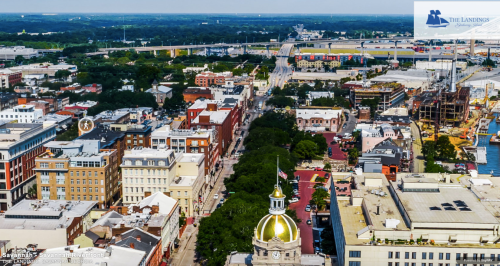 Aerial view of Savannah, Georgia, showcasing historic buildings, tree-lined streets, and a distant bridge.