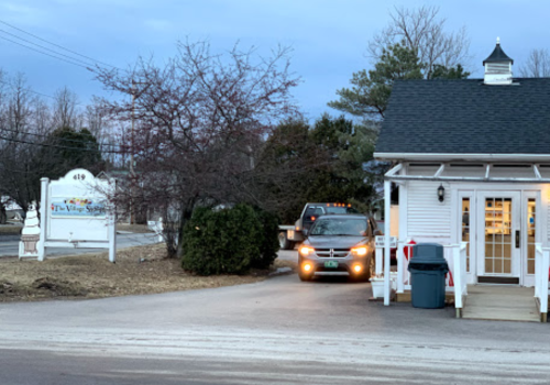 A vehicle approaches a small building with a sign reading "The Village Spa" amidst bare trees and a cloudy sky.