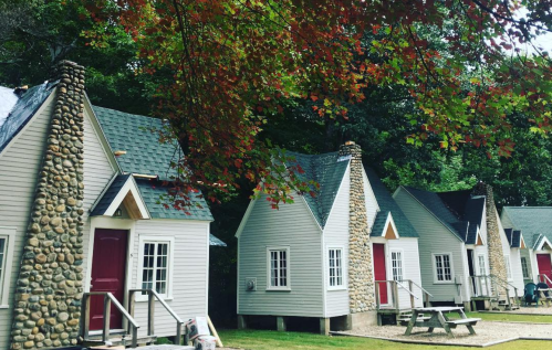 Charming cottages with stone chimneys, surrounded by trees with autumn leaves.
