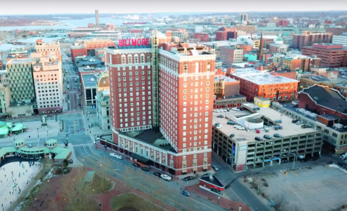 Aerial view of a cityscape featuring the Biltmore Hotel and surrounding buildings, with a parking garage nearby.