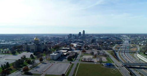 Aerial view of a city skyline with a prominent dome building, highways, and open green spaces.