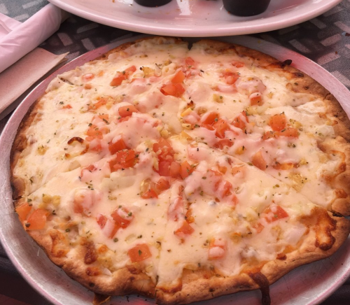 A freshly baked pizza topped with melted cheese and diced tomatoes, served on a silver platter.