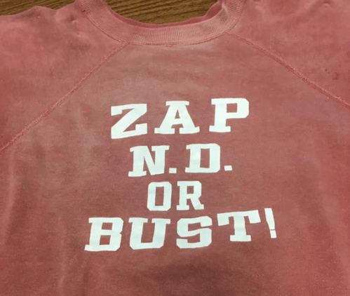 A faded red sweatshirt with the text "ZAP N.D. OR BUST!" printed in bold white letters.