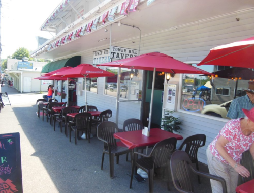 Outdoor seating area of a restaurant with red umbrellas, tables, and a sign that says "OPEN."