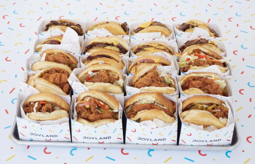 A colorful display of various sandwiches in branded boxes, arranged neatly on a confetti-patterned background.