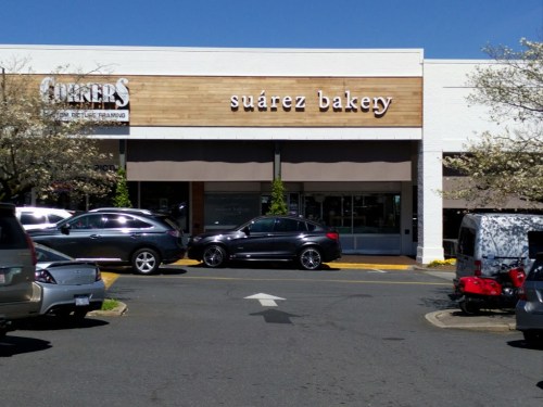 Exterior of Suárez Bakery with a clear blue sky and parked cars in front.