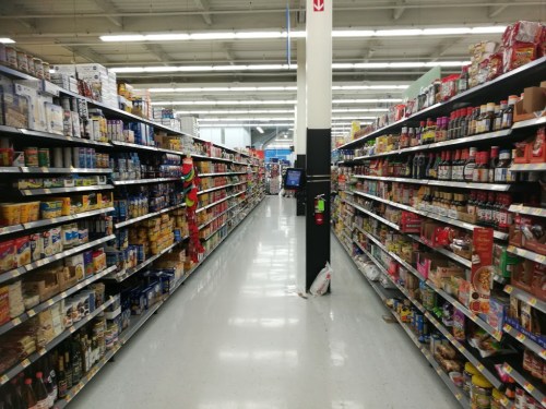 A grocery store aisle filled with various food products on both sides, with a clear path down the center.