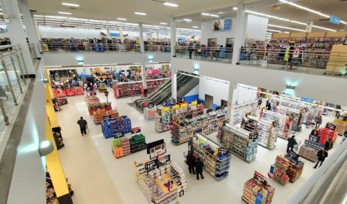 Aerial view of a large retail store with aisles filled with products and shoppers throughout the spacious layout.
