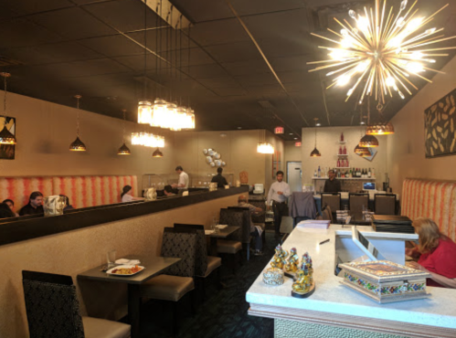 Interior of a restaurant featuring modern decor, tables, and staff serving customers. Warm lighting and a cozy atmosphere.