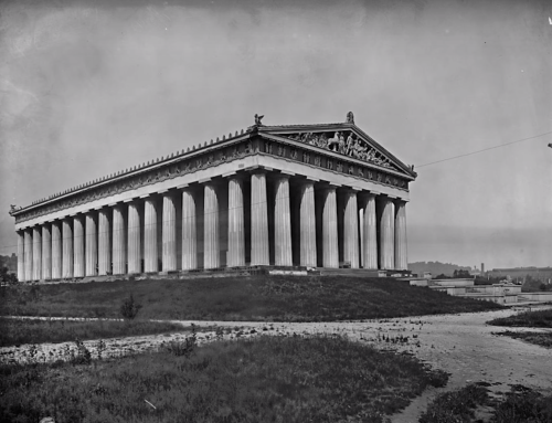 A historic black-and-white photo of a grand temple with tall columns, set on a grassy hill.