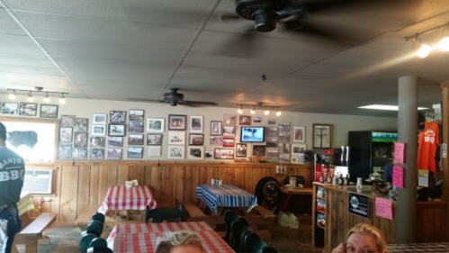Interior of a casual restaurant with checkered tablecloths, wall photos, and a fan overhead. A cozy, inviting atmosphere.