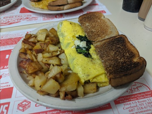 A plate of breakfast featuring an omelette, toast, and seasoned potatoes.