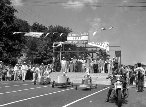 A black-and-white photo of a soapbox derby event in 1937, with spectators and racers lined up at the starting line.