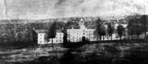 Black and white image of a historic building surrounded by trees, set against a hilly landscape.