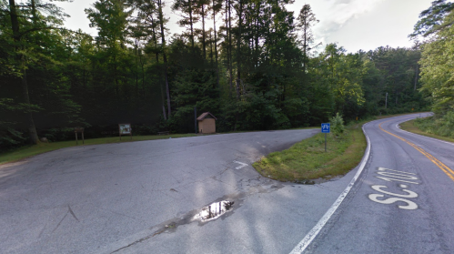 A fork in the road surrounded by trees, with a sign for SC-107 and a small building on the left.