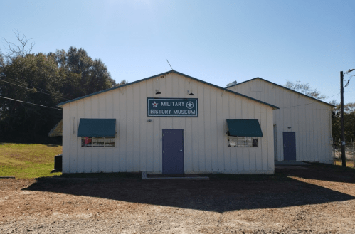 Exterior of a white building with a sign reading "Military History Museum" under a clear blue sky.