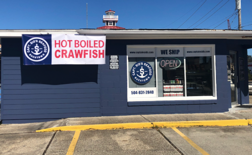 A seafood shop with a sign advertising "Hot Boiled Crawfish" and an open sign in the window.