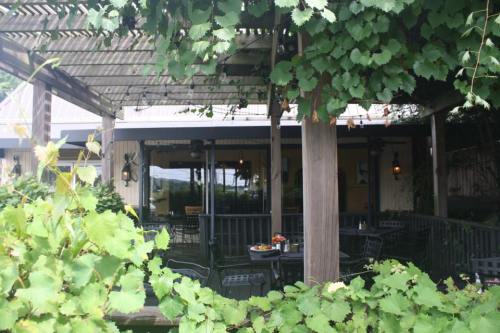 A cozy outdoor dining area surrounded by green vines and plants, with tables set for guests.
