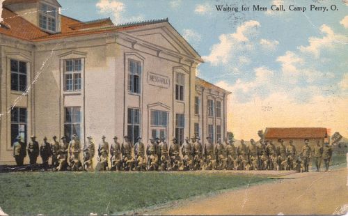 A historic postcard showing soldiers lined up outside a building at Camp Perry, Ohio, waiting for mess call.