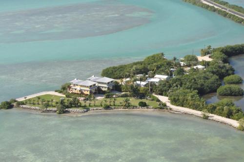 Aerial view of a coastal property surrounded by turquoise waters and lush greenery.