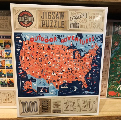 A colorful jigsaw puzzle box featuring a map of the USA with outdoor activities and landmarks illustrated. 1000 pieces.