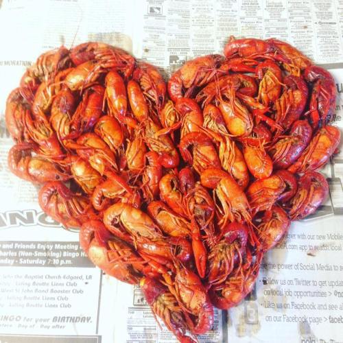 A heart shape made of cooked crawfish arranged on newspaper.