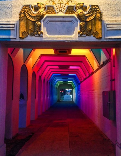 A colorful, illuminated archway with decorative eagles at the entrance, leading into a vibrant corridor.