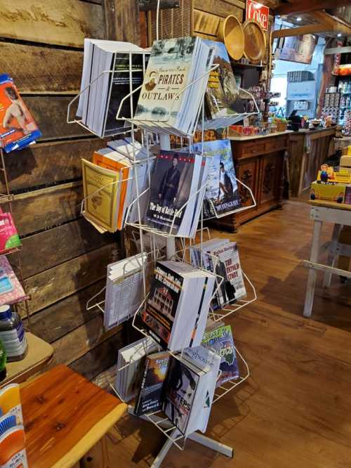 A rotating display rack filled with various books in a rustic store setting.