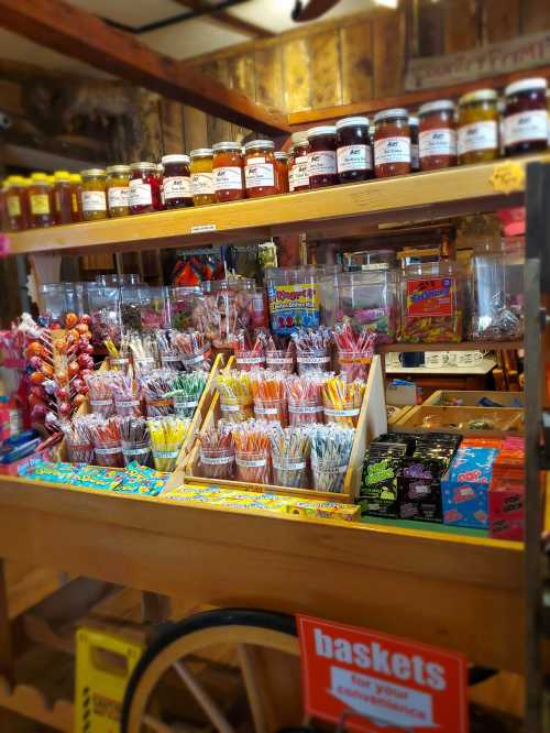 A colorful display of candies and jars of jam on a wooden cart in a rustic shop.