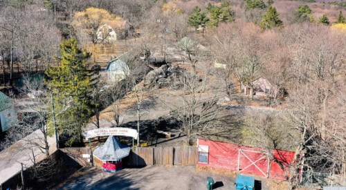 Aerial view of Crystal Game Farm, featuring bare trees and rustic buildings in a wooded area during autumn.
