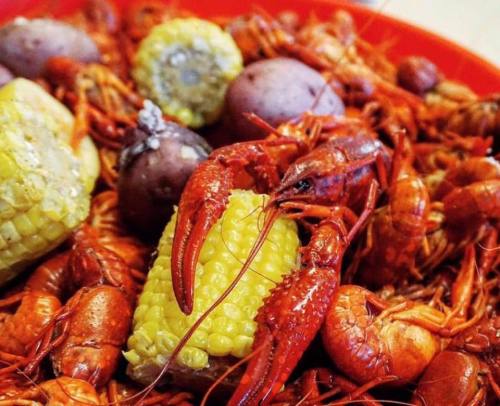 A vibrant dish of crawfish, corn, and purple potatoes, showcasing a mix of seafood and vegetables.