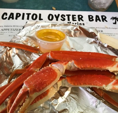 A plate of steamed crab legs with a side of melted butter, set on a table with a menu in the background.